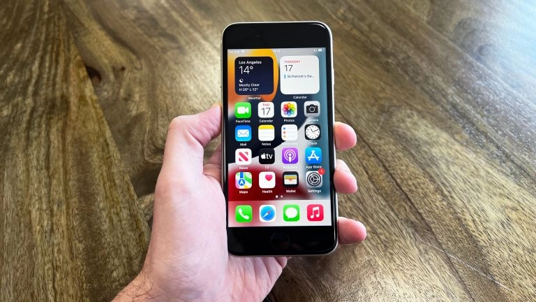 iPhone SE 2022 và Xiaomi Redmi Note 13 trong tay người dùng, thể hiện sự nhỏ gọn và màn hình lớn.